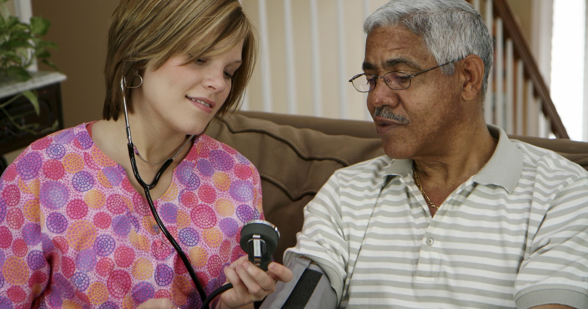 A young nurse checks blood pressure on senior man
