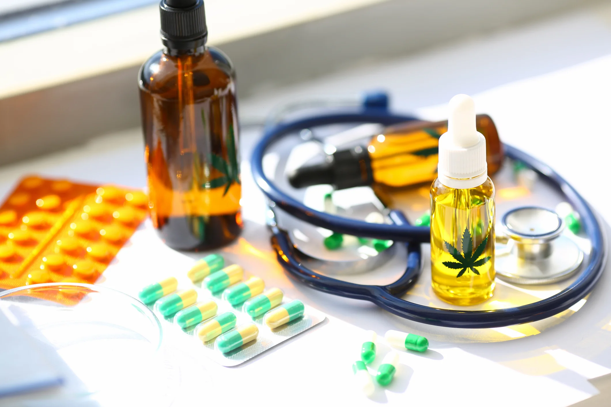 Close-up of cannabinoid oil in bottle and capsules lying on table. Medical marijuana for pain-relieving. Medication for sick patient. Treatment of diseases with organic and natural ingredients