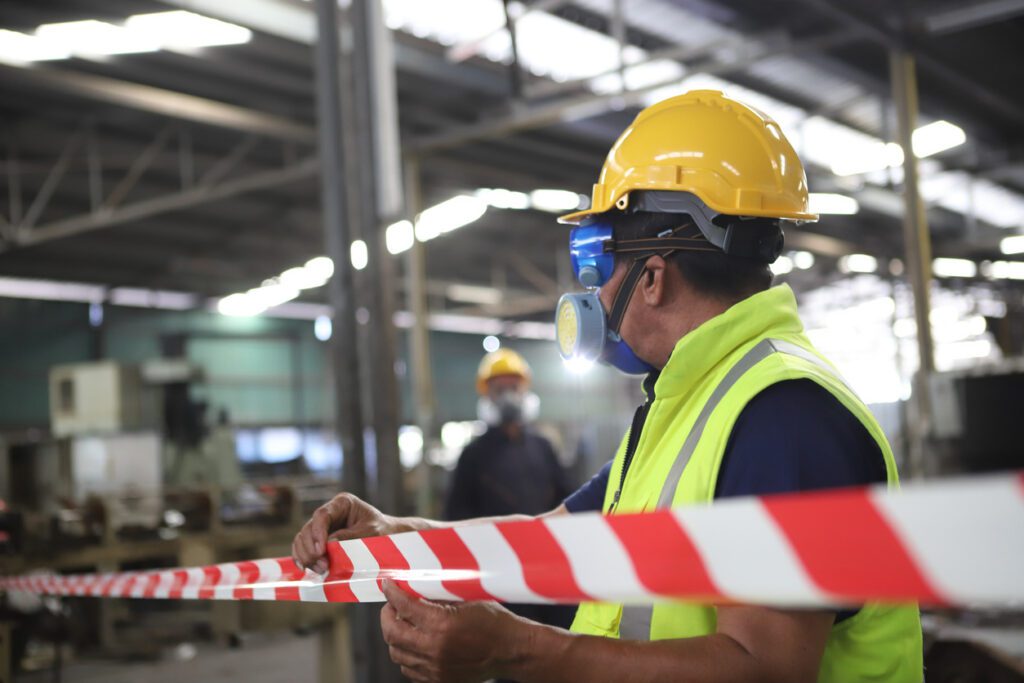 Employee puts up a red and white warning ribbon in a factory