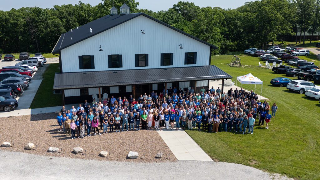 Group photo of employees gathered outside the company headquarters.