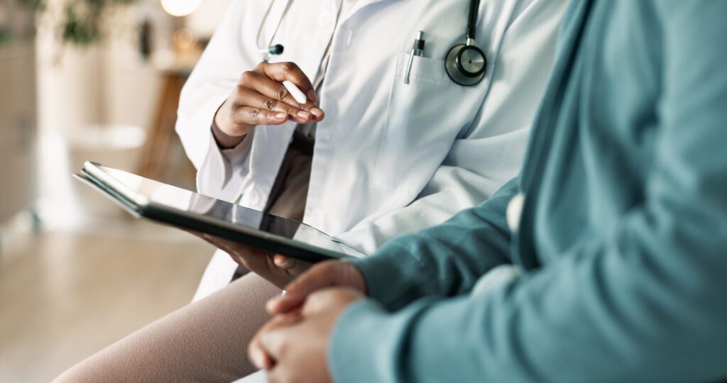 Tablet, hands and patient with doctor in hospital for consultation with cold, flu and sickness. Digital technology, conversation and person with healthcare worker for medical diagnosis in clinic.