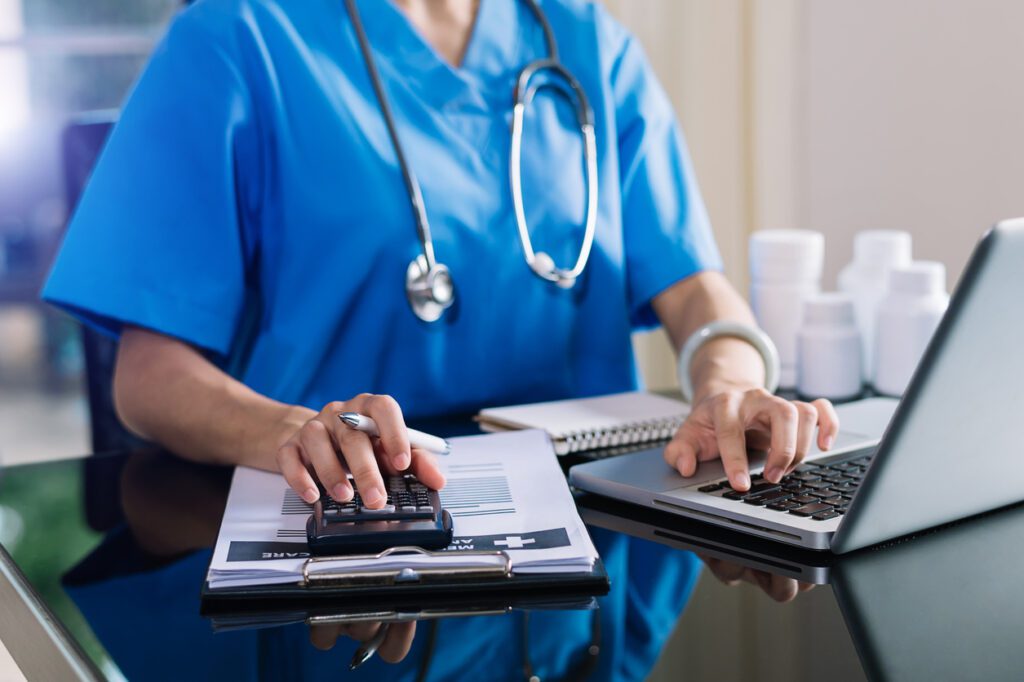 Hand of a smart doctor used a calculator and smartphone for the calculate healthcare costs and fees.