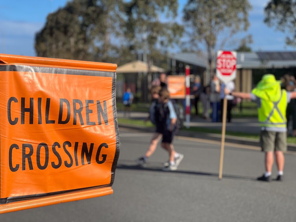 children crossing the street as a crossing guard stops traffic