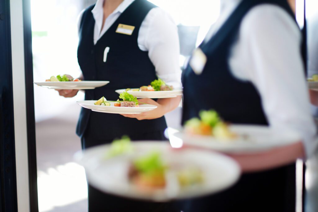 Waiter carrying plates with meat dish on some festive event, party or wedding reception