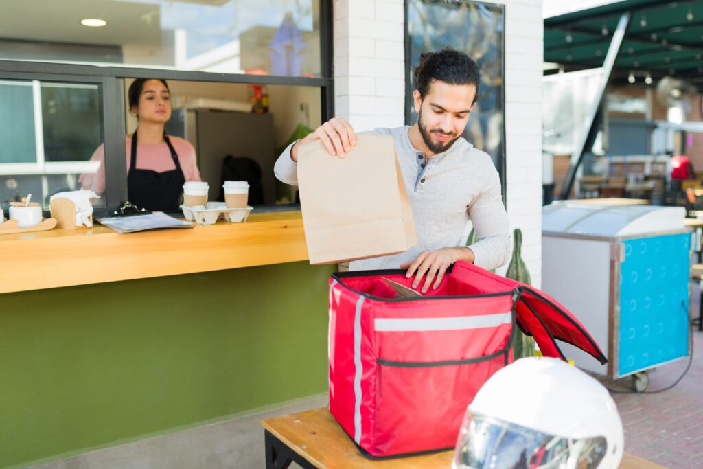 Coffee shop and restaurant handing food and drinks to-go to the delivery person