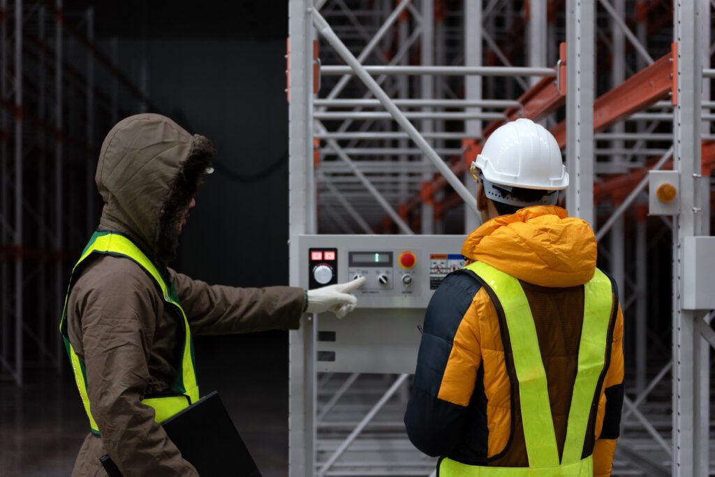 Maintenance technician service in cold warehouse storage, Machinery engineering people checking moving rack system and equipment in warehouse.
