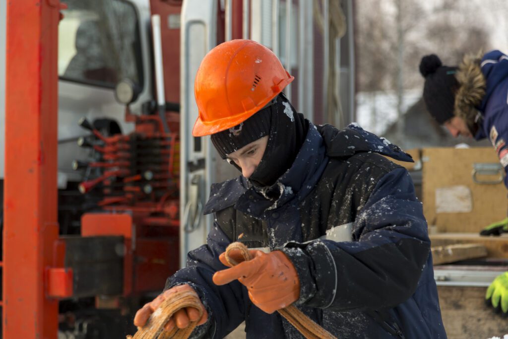 Portrait of a fitter slinger in an orange vest and helmet on unloading ice plates