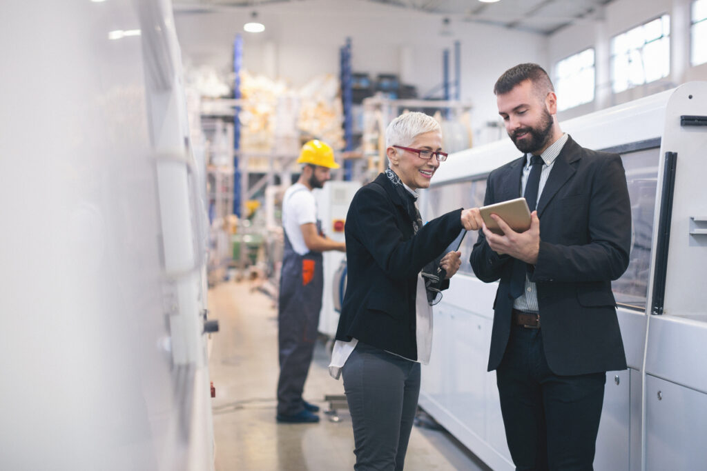 A male employee and a female employee in a factory looking at a tablet
