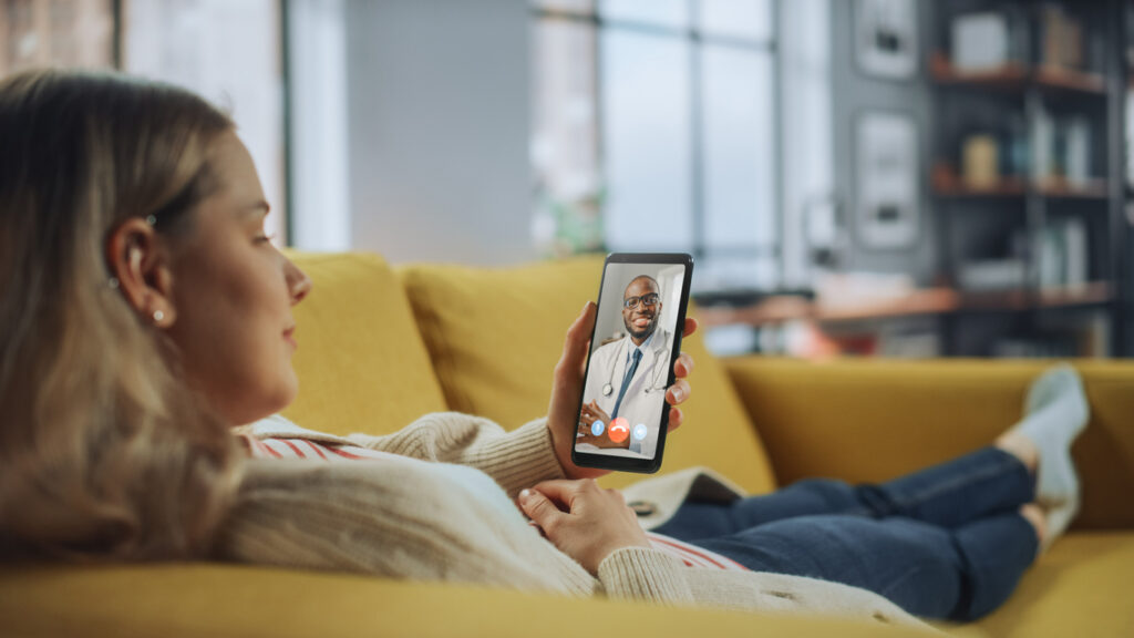 Close Up of a Female Chatting in a Video Call with Her Male Family Doctor on Smartphone from Living Room. Ill-Feeling Woman Making a Call from Home with Physician Over the Internet.