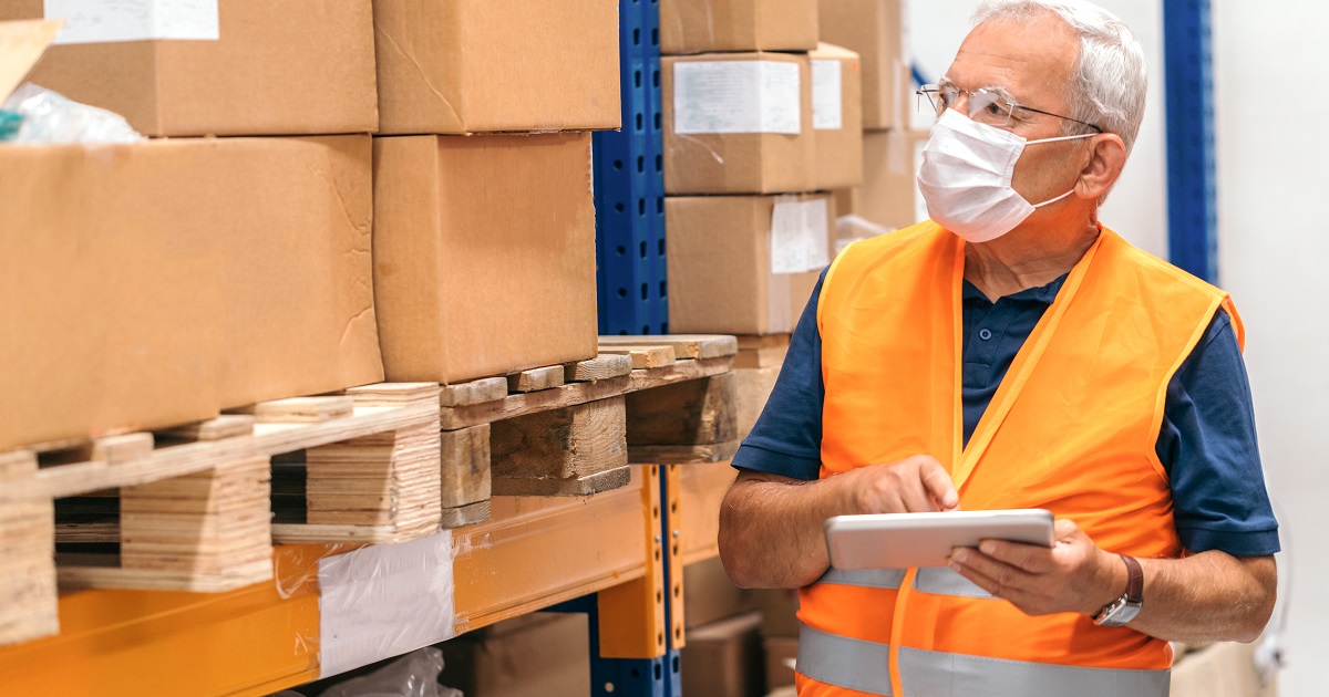 Warehouse employee takes stock wearing a hygienic mask